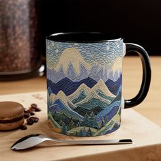 a coffee mug sitting on top of a wooden table next to a spoon and cup