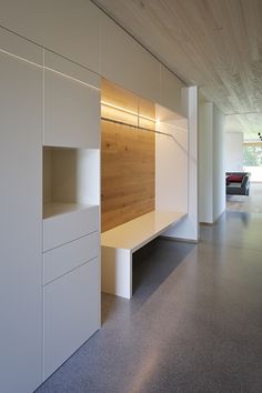 an empty room with white furniture and wood paneling on the walls, along with concrete flooring