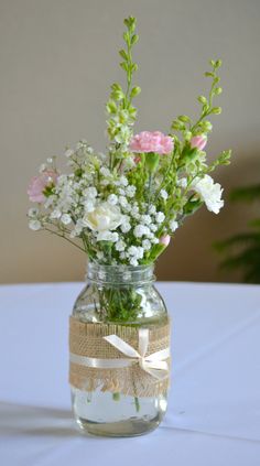 a vase filled with lots of flowers on top of a white tablecloth covered table