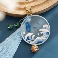 a blue and white embroidered keychain hanging from a wooden hook