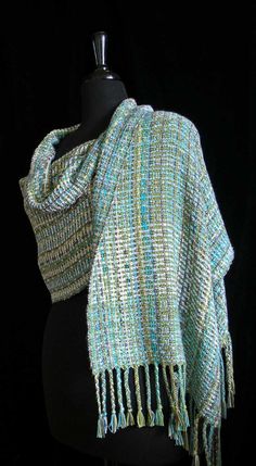 a green and blue shawl on a mannequin head with fringes around it