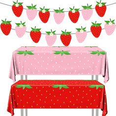 a pink table topped with a red bench covered in strawberries next to a string of lights