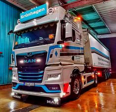 a large semi truck parked inside of a garage next to a blue wall with the word man written on it