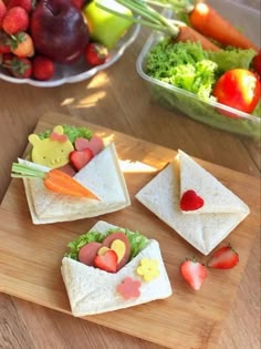 sandwiches with fruit and veggies on them sitting on a cutting board