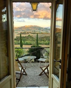 an open door leading to a patio with two chairs and a table in the middle