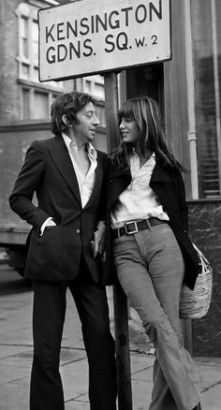 a man and woman standing next to a street sign