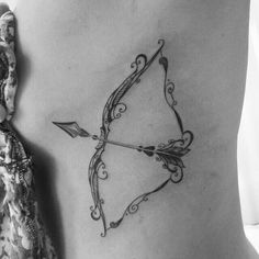 an arrow tattoo on the back of a woman's stomach