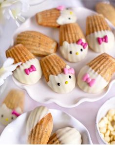 hello kitty cookies on plates with flowers and marshmallows next to them for dessert