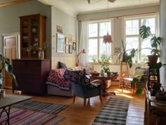 a living room filled with furniture and lots of plants on the windows sills