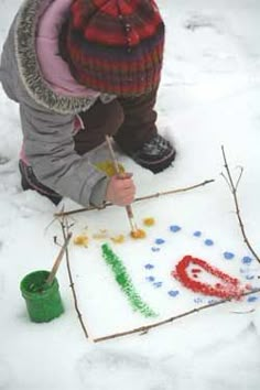 a young child is painting letters in the snow