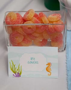 there is a container full of jelly candies with a card on the table next to it