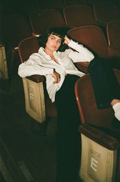 a woman sitting in a chair with her hands on her head and looking off to the side