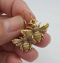 Gold Honey Bee Earrings - Simple, Delicate, realistic. Minimalist Design with small gold toned ear wires. These Gold Honey Bee Earrings are gold toned, lightweight, and delightful to wear with clear rubber ear wire guards included. Your Gold Honey Bee Earrings will arrive in a small organza pouch with a matching polishing cloth. Gift packaging cheerfully provided upon request! Honey Bee Earrings, Wire Jewelry Patterns, Dragon Earrings, Organza Pouch, Bee Jewelry, Gold Bee, Dragonfly Earrings, Bee Earrings, Earrings Simple