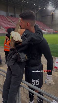 a man and woman embracing each other in front of a stadium