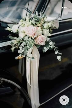 a bouquet of flowers is tied to the side of a black car with its door open