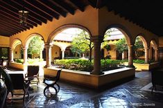 an outdoor courtyard with seating and trees in the background at night, surrounded by arches