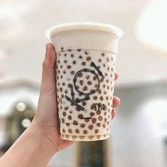 a hand holding up a coffee cup with the word q on it's side