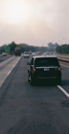 the back end of a black car driving down a highway