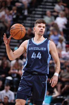 a basketball player is about to pass the ball in front of an audience at a sporting event