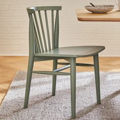 a wooden chair sitting on top of a rug next to a table with a bowl