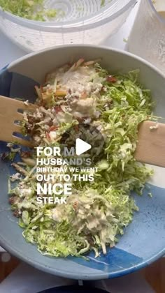 a bowl filled with lettuce and salad being stirred by a wooden spatula