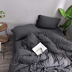 an unmade bed with a book on it in a room next to a table