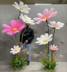 a man is standing in front of some fake daisies and grass with flowers on them