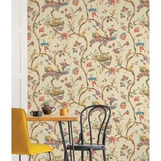 two chairs and a table in front of a wallpapered room with floral designs