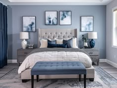 a bedroom with blue walls and pictures on the wall above the bed, along with a footstool