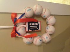 a baseball wreath hanging on the door with an ornament and ribbon around it