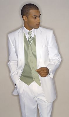 a man in a white suit and green tie is posing for a photo with his hands in his pockets