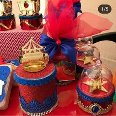 a table topped with red and blue cakes covered in frosted icing, crown hats and ribbons