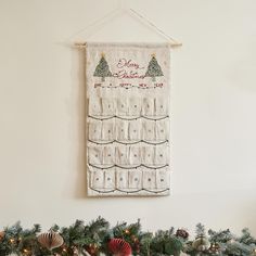 a christmas banner hanging on the wall above a fireplace mantle with stockings and ornaments around it