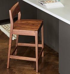 a wooden stool sitting on top of a hard wood floor next to a white counter