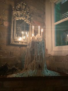 there are many candles that are lit on the table in front of the mirror and window