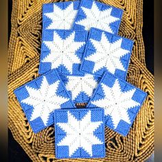 four blue and white knitted coasters sitting on top of a wicker basket