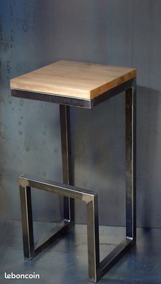 a wooden table sitting on top of a metal frame next to a white wall and floor