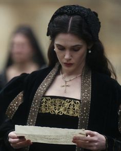 a woman in black and gold dress walking down the street with other people behind her