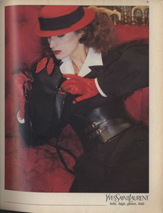 a woman in red hat and gloves sitting on a couch holding a black glove with one hand