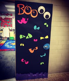 a bulletin board with the word boo on it and eyes painted on it in front of a brick wall