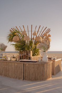 an outdoor bar with palm trees and vases on the counter next to the ocean