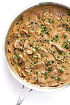 a pan filled with mushrooms and gravy on top of a white countertop