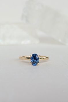 Blue sapphires come in all shades and clarity - this oval-shaped gem is wonderfully clear and sparking, with a rich, deep shade of blue that can change to more purple in different lighting. We've set this sapphire in a simple, airy prong with two tiny white diamonds under it. The overall effect is one of whimsy and delicacy, but this ring will be an heirloom for generations. - 1.45ct sapphire﻿- 0.03ctw diamonds﻿- 14k recycled yellow gold﻿- 2mm band﻿- High polish finish ﻿This ring ships immediate Timeless Blue Sapphire Ring, Timeless Blue Oval Sapphire Ring, Timeless Oval Sapphire Ring With Prong Setting, Timeless Oval Sapphire Ring, Classic Blue Sapphire Ring With Oval Cabochon, Oval Sapphire Promise Ring With Ethical Diamonds, Timeless Blue Sapphire Birthstone Ring, Blue Sapphire Oval Ring, Oval Sapphire Promise Ring