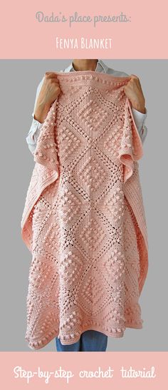 a woman is holding up a pink knitted sweater