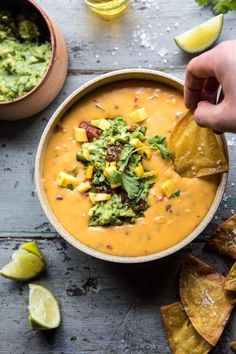 a person dipping tortilla chips into a bowl of guacamole