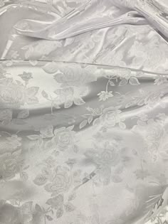 the fabric is shiny and white with flowers on it's side, as well as silver foil