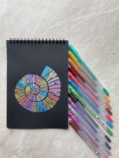 a spiral notebook with colored crayons next to it