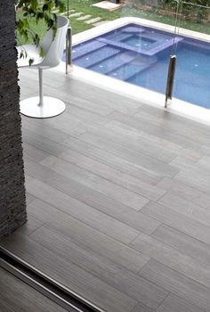 an empty swimming pool in the middle of a patio with wooden flooring and glass doors