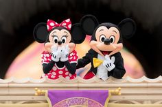 two mickey and minnie mouse figurines standing on top of a stage at disney world