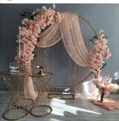 a table with flowers and candles on it next to a round metal stand that has sheer draping